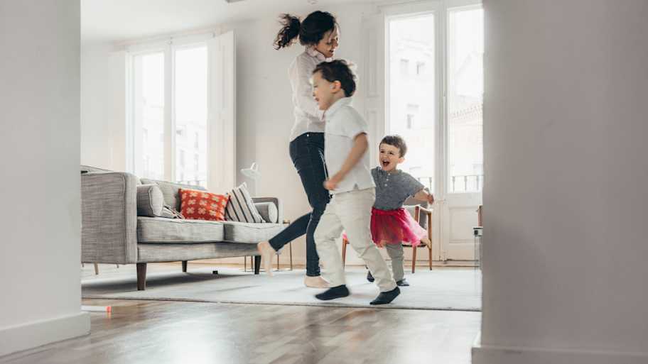 Mother and children jumping and dancing in the living room 